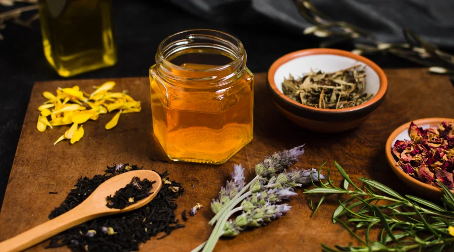 Jar of Kashmiri honey with dried herbs and spices on wooden table